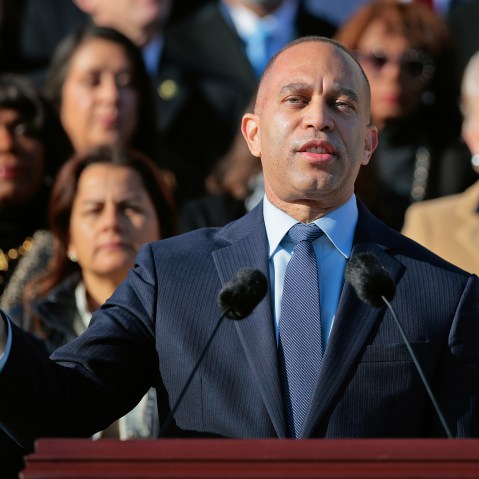 Hakeem Jeffries stands at a podium in front of a crowd of other Democratic leaders.