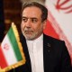 Iranian Foreign Minister Abbas Araghchi with an Iranian flag in front of him and behind him.