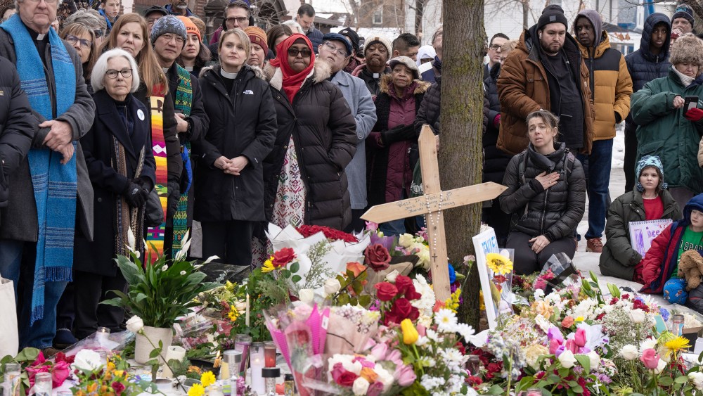 People surround a memorial of flowers.