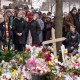 People surround a memorial of flowers.