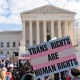 People hold signs supporting trans rights outside the Supreme Court.