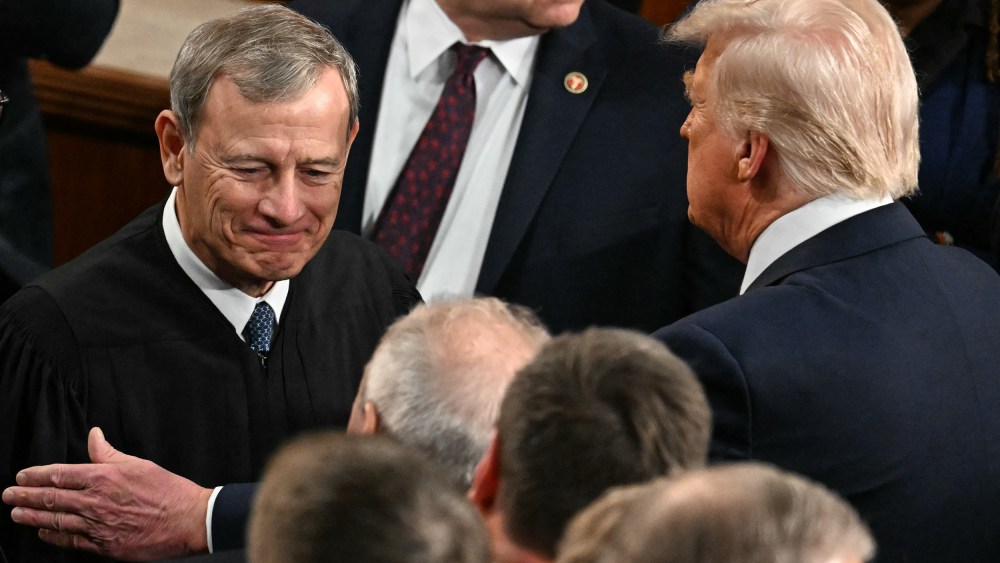 President Trump, right, pats Chief Justice Roberts arm ina crowd of people.