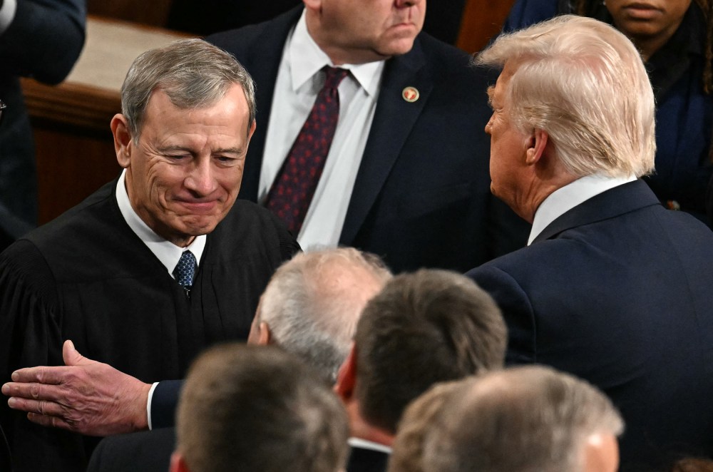 President Trump, right, pats Chief Justice Roberts arm ina crowd of people.