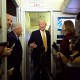 Donald Trump in a doorway on Air Force One, surrounded by reporters and Senator Lindsey Graham.