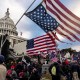 People, many with American flags, surround the Capitol.