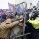 Police officers in yellow jackets and helmets push against Jan. 6 demonstrators near the U.S. Capitol.