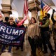 People within the Capitol hold flags supporting Donald Trump.