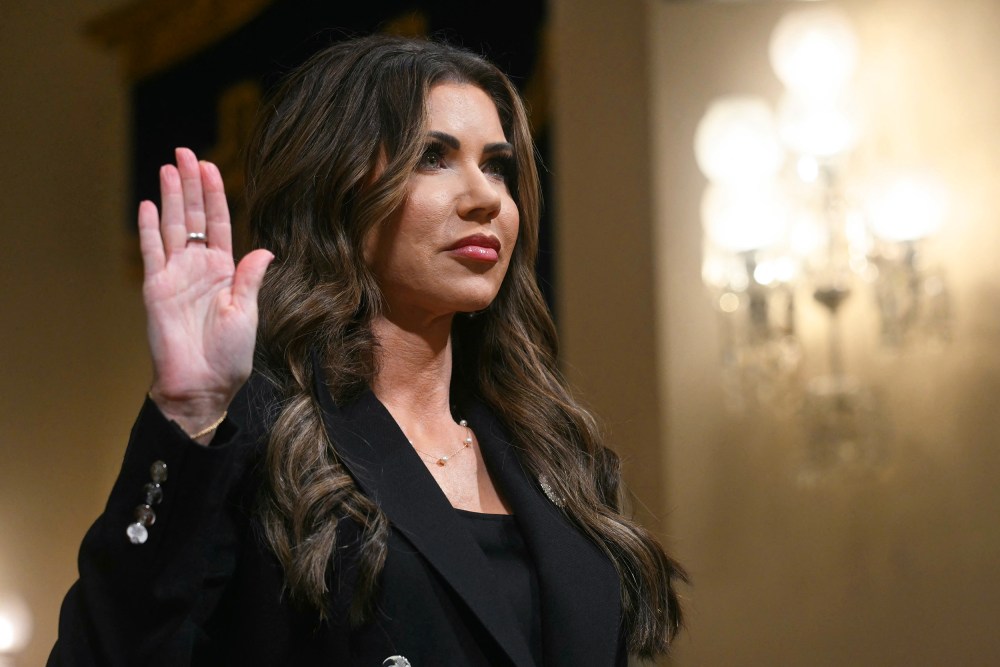 Kristi Noem with her right hand raised.