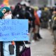 A protestor holds a sign as federal agents stand guard as protestors gather outside the Bishop Henry Whipple Federal Building in Saint Paul, MN.