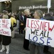 People hold signs reading "Who will ask the questions" and "Less news we all lose" outside the Pittsburgh Post-Gazette building.