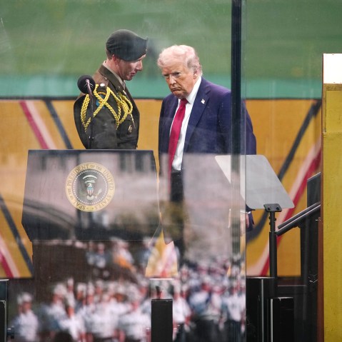 President Trump talks to a member of the U.S. military on the podium as the parade goes on.