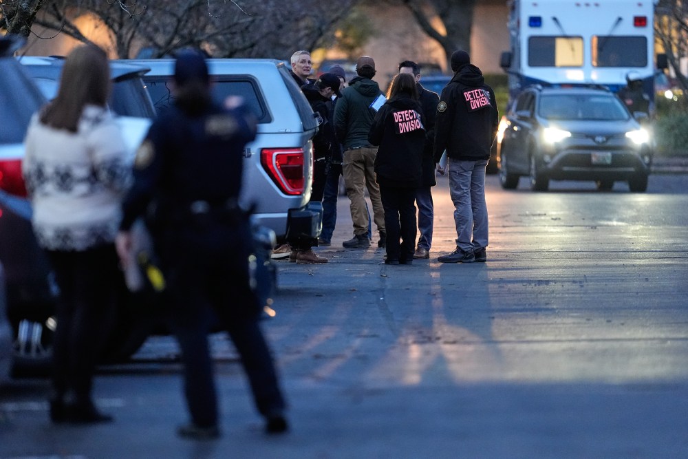 Members of the law enforcement stand in the street at dusk.