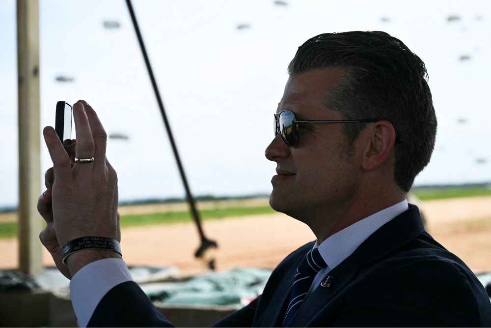 US Secretary of Defense Pete Hegseth holds up his phone to film during a military demonstration.