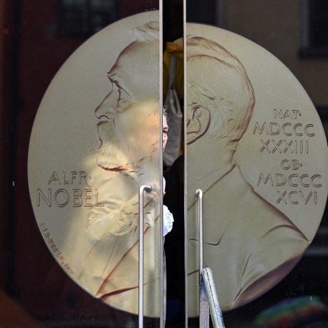 A woman opens the door, one with the Alfred Nobel coin imprinted on it, to leave the Swedish Academy.