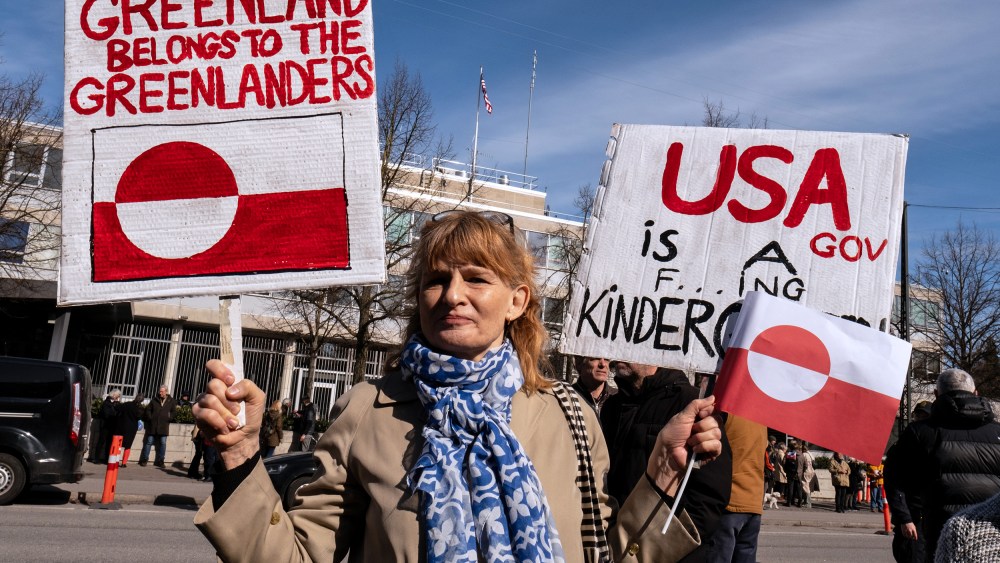 A person holds signs condemning U.S. pressure on Greenland and Denmark.