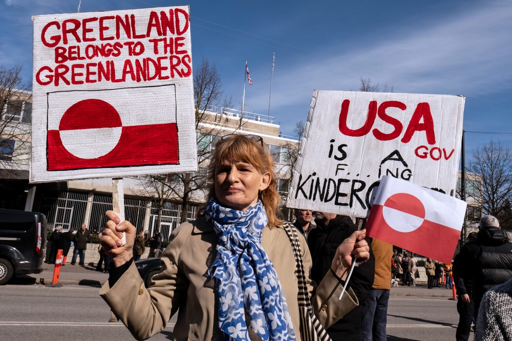 A person holds signs condemning U.S. pressure on Greenland and Denmark.