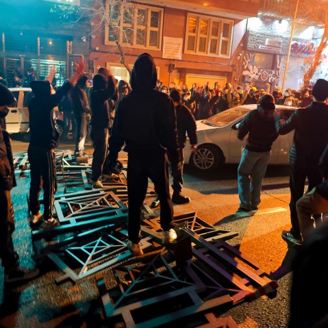 A big group of protestors stand on the street.