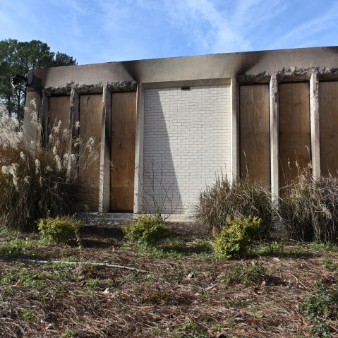 Boards cover parts of an abandoned-looking building.