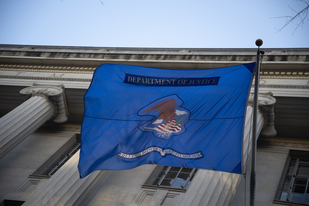 Department of Justice&rsquo;s blue flag is hung in front of the building, waving in the wind.