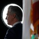 Gavin Newsom backlit, next to a California state flag.
