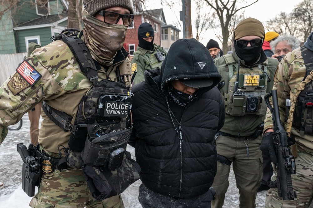 Federal agents wearing body cams detain a person.