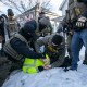 Masked ICE agents handcuff a person facedown in the snow.