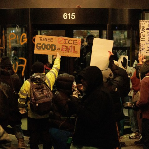 Protestors holding signs in front of Graduate Hotel in Minneapolis. There are some writings on the hotel windows, insulting ICE agents.