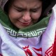 A young woman, wrapped in an Iranian flag, cries.