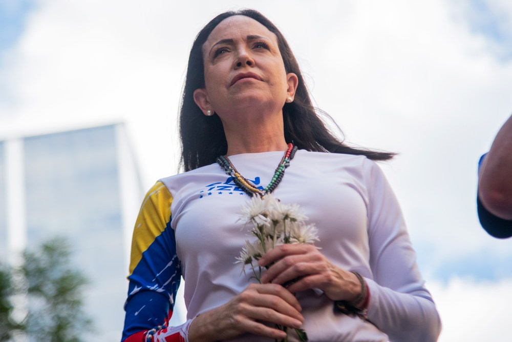 Mar&iacute;a Corina Machado gazes forward with flowers in her hands.