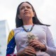 María Corina Machado gazes forward with flowers in her hands.