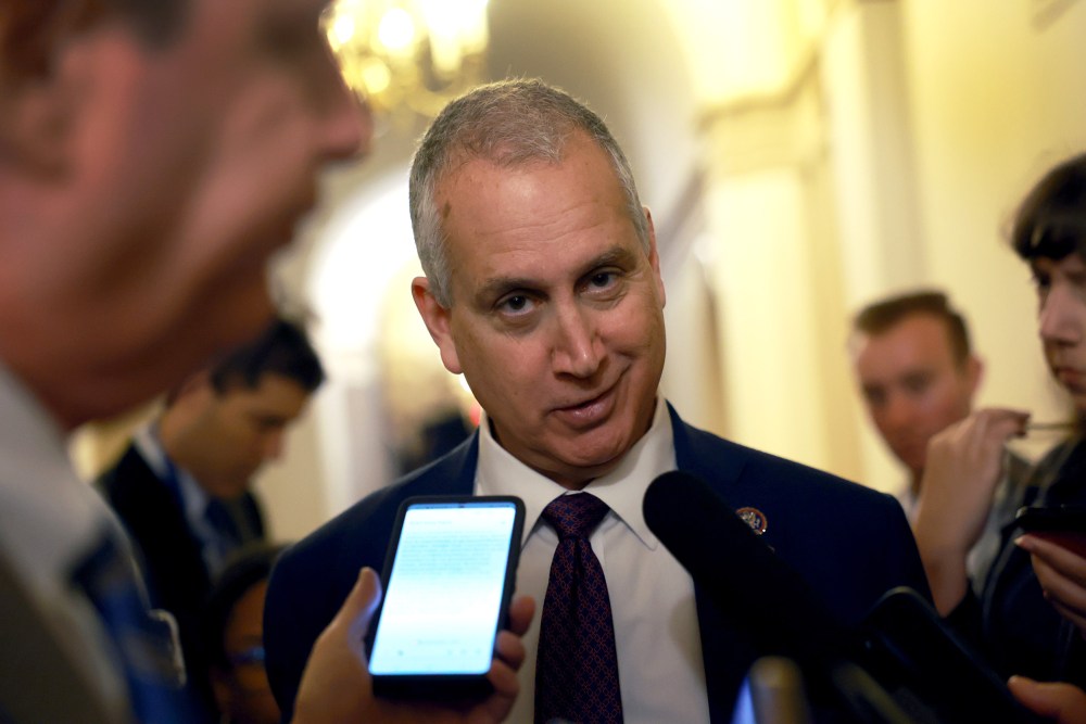 Mario Díaz-Balart looks at the camera as microphones are held to his face.