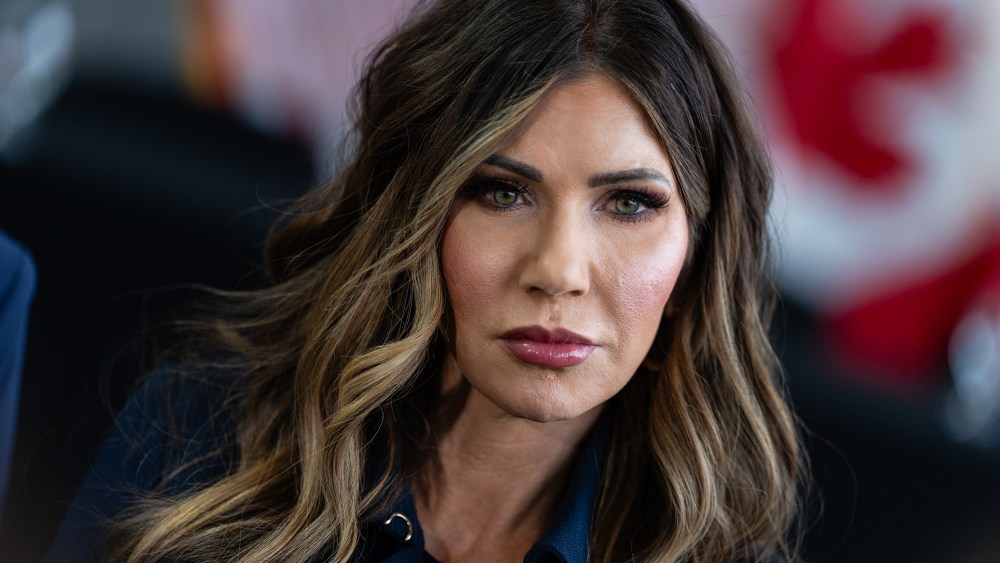 A tight tilted photo of Kristi Noem shows her displeased.