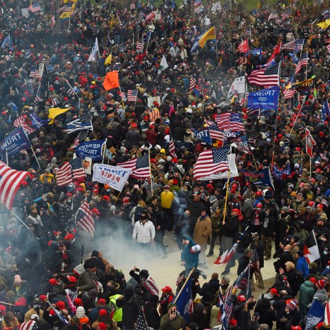 A crowd of people, many carrying Trump flags and American flags.