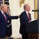 President Donald Trump pats the back of John Hess as he delivers remarks on June 12, 2025 in the East Room of the White House.