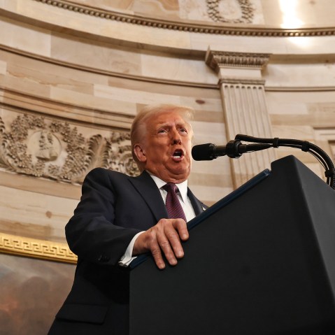 President Donald Trump speaks into a microphone at a podium.