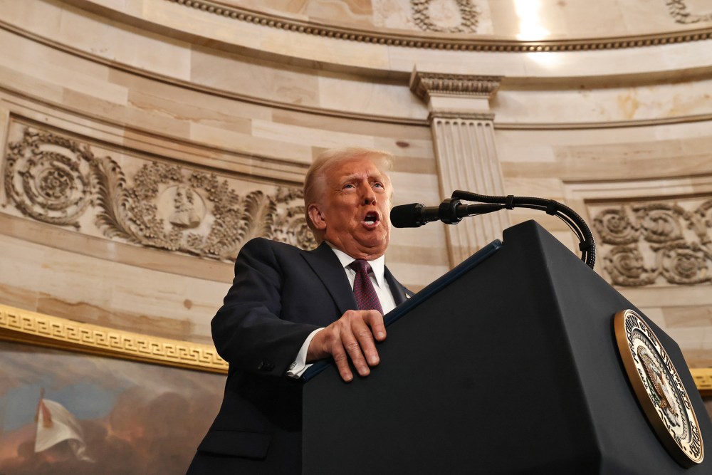 President Donald Trump speaks into a microphone at a podium.
