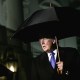 President Trumps walks out of White House at night, holding a black large umbrella.