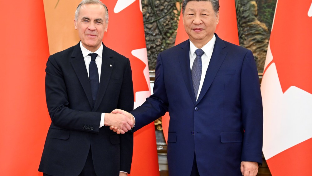 Canadian Prime Minister, left, and Chinese President shake hands as they pose for a portrait in front of the countries' flags.