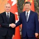 Canadian Prime Minister, left, and Chinese President shake hands as they pose for a portrait in front of the countries' flags.