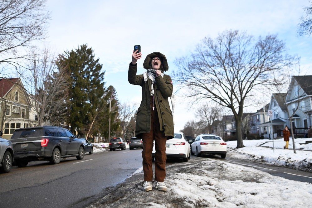 A person yells while holding up a cell phone.