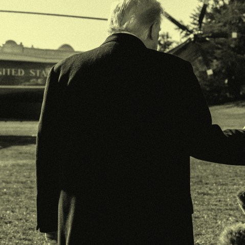 A sepia toned image shows Trump from behind, waving to reporters as he walks toward the Marine One helicopter