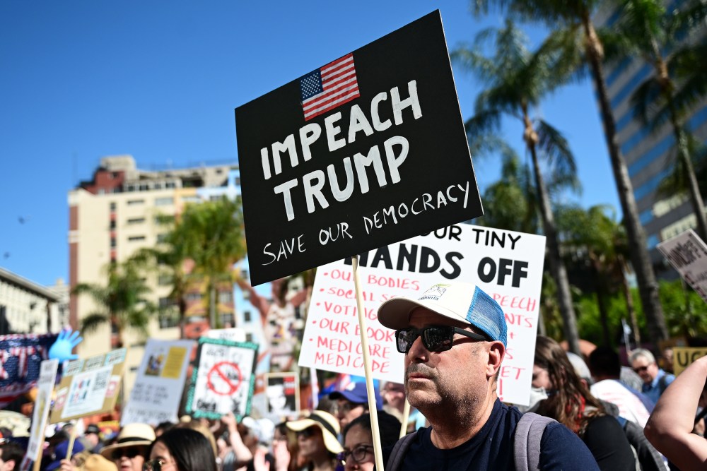 A protester holds a sign reading "Impeach Trump" during a "Hands Off!" rally in on April 05, 2025 in Los Angeles.