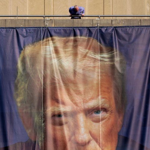 A person inspects a giant banner with the image of President Donald Trump hanging on the outside of the U.S. Department of Labor.
